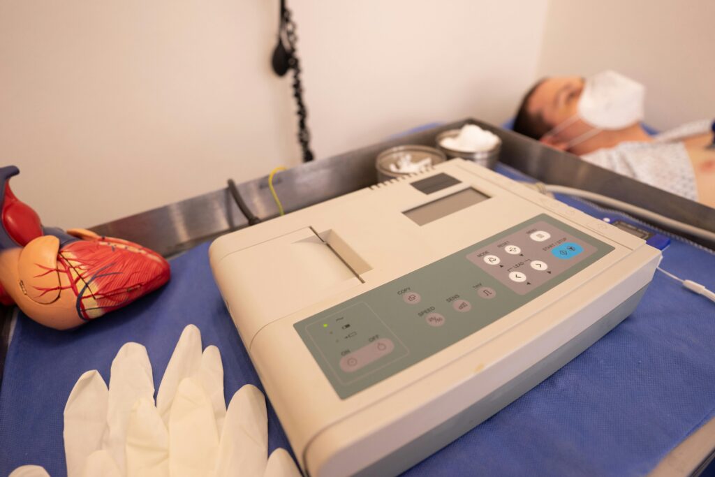 Close-up of ECG machine and model heart in a hospital setting.